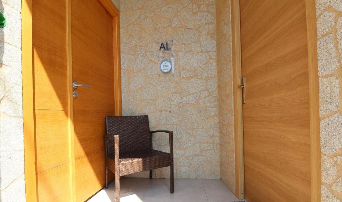 Entrada da casa, com portas de madeira e placa de Alojamento Local